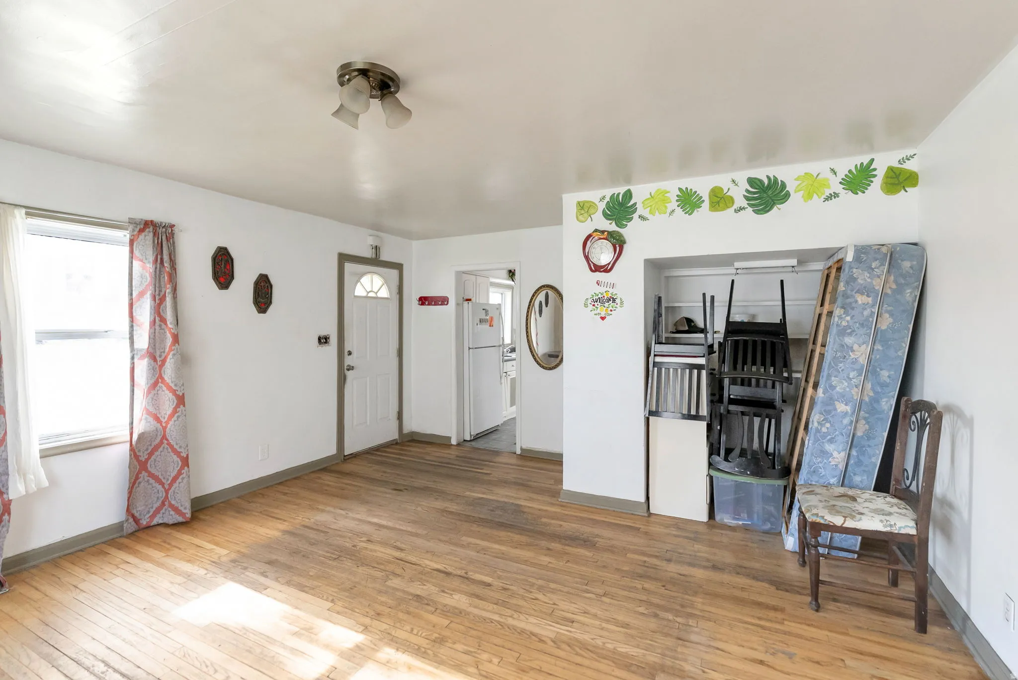 Bright room featuring wood-finish flooring, white walls, and a window with natural light