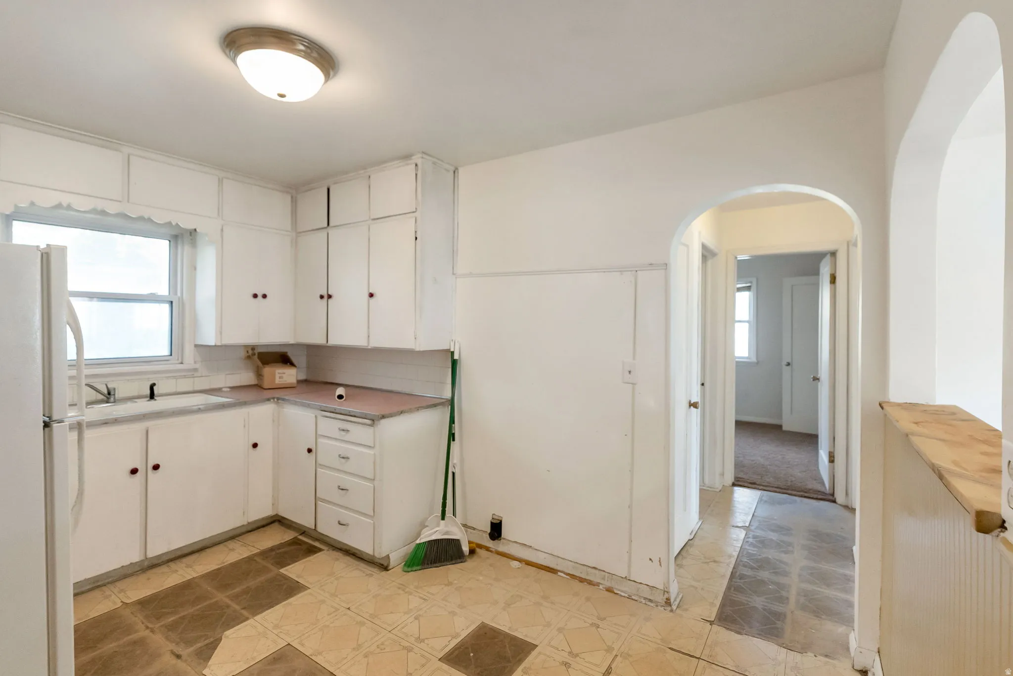 Kitchen with white cabinetry, a corner sink with window, and a built-in pantry