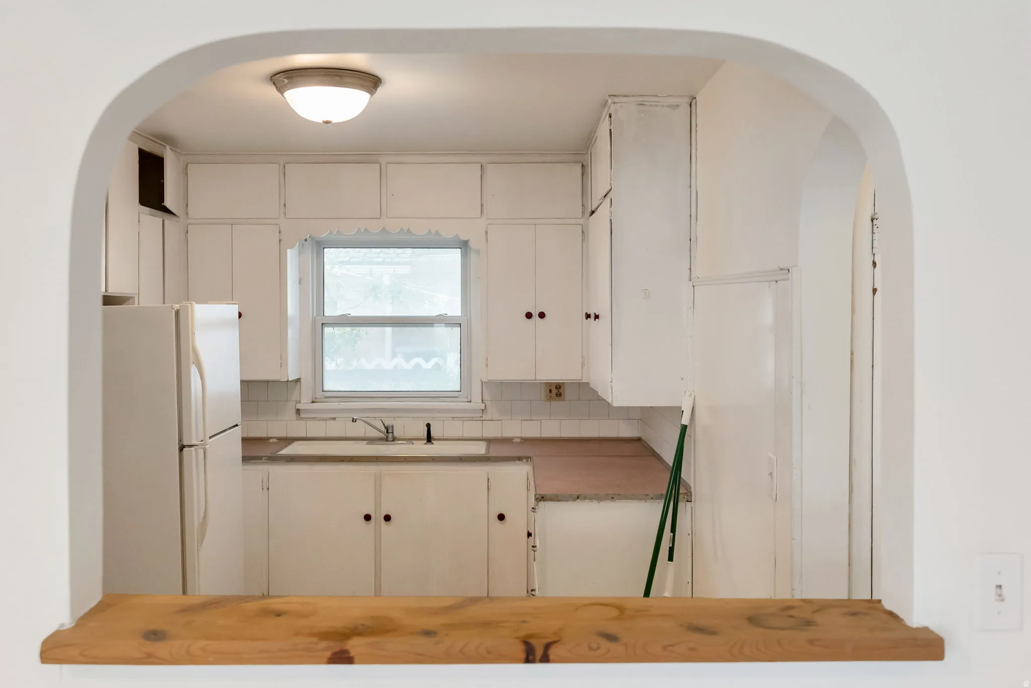 Kitchen featuring a window, white cabinetry, a built-in sink, and light-colored countertops