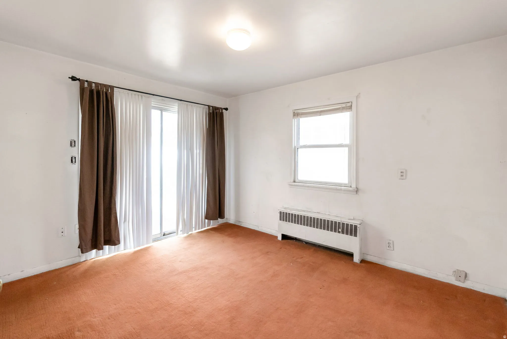 Room with sliding glass door, single window, and wall-mounted radiator