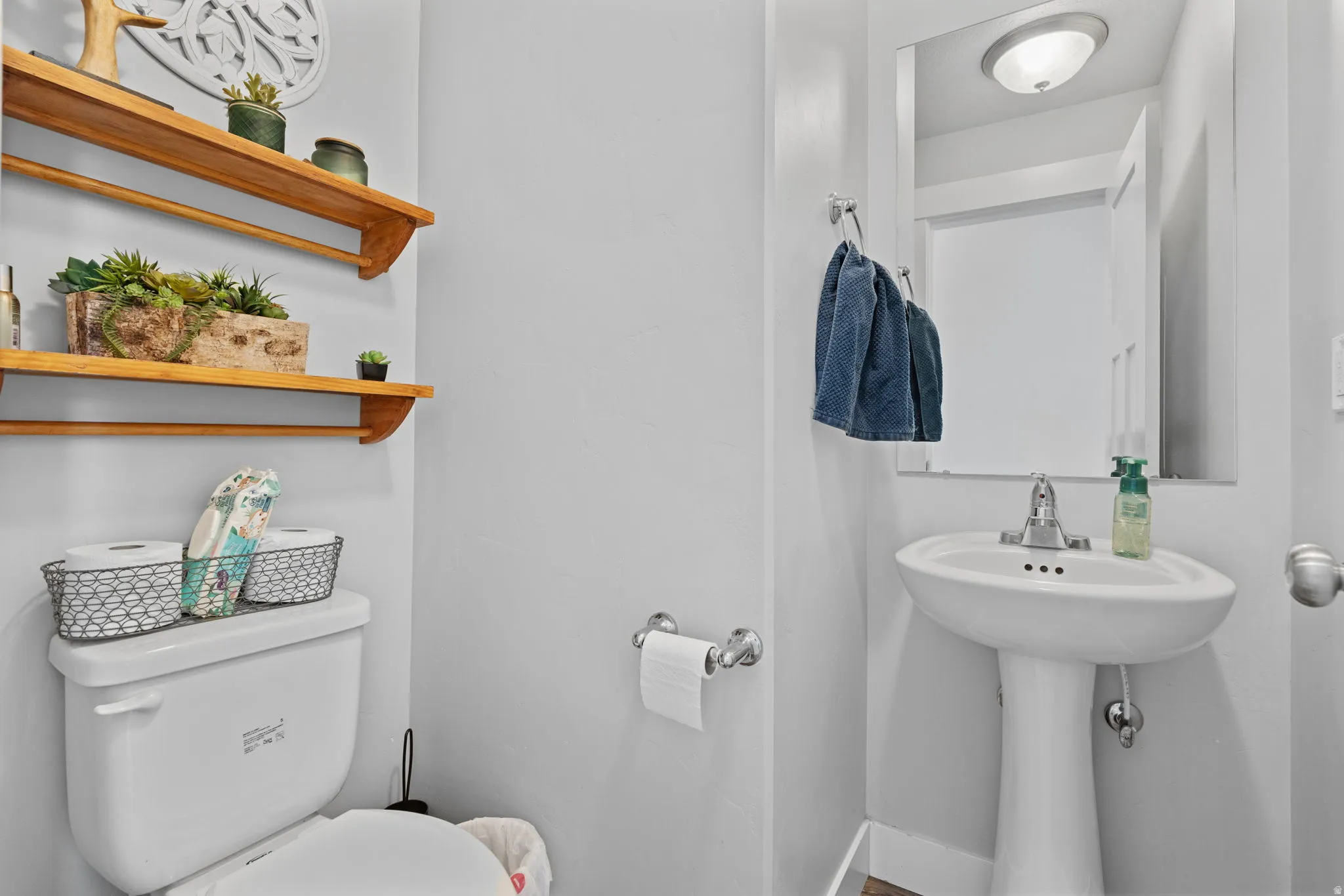 Pedestal sink with chrome faucet, framed mirror, and overhead lighting