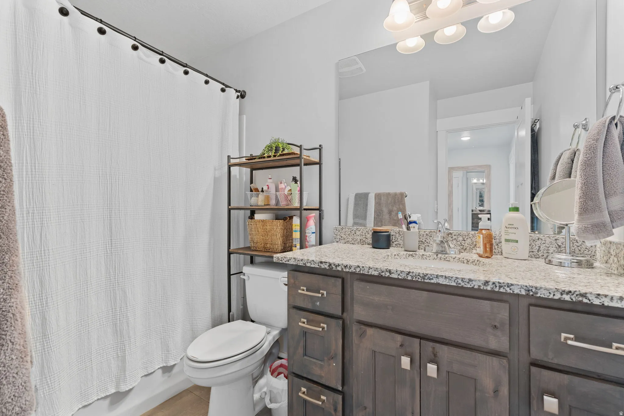 Bathroom vanity featuring a granite countertop with a dual sink and brushed nickel faucets
