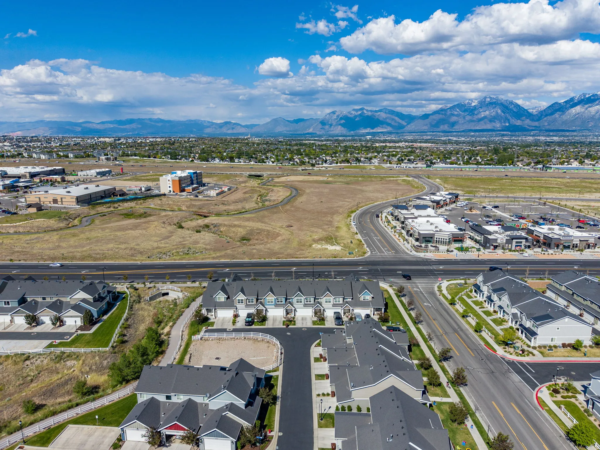 Aerial panorama showcasing residential properties under a dynamic sky with distant mountains