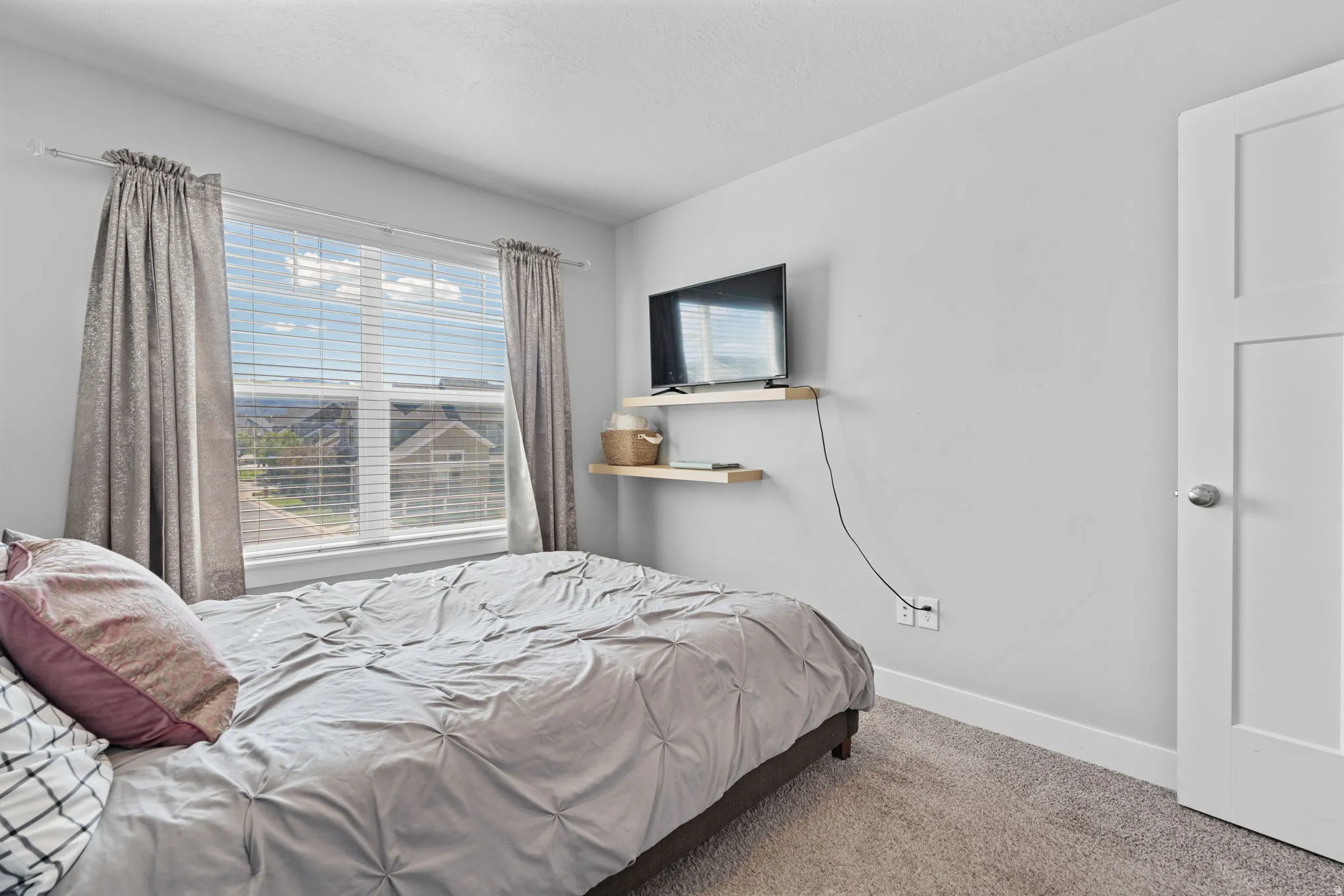 Carpeted room with a large window featuring horizontal blinds