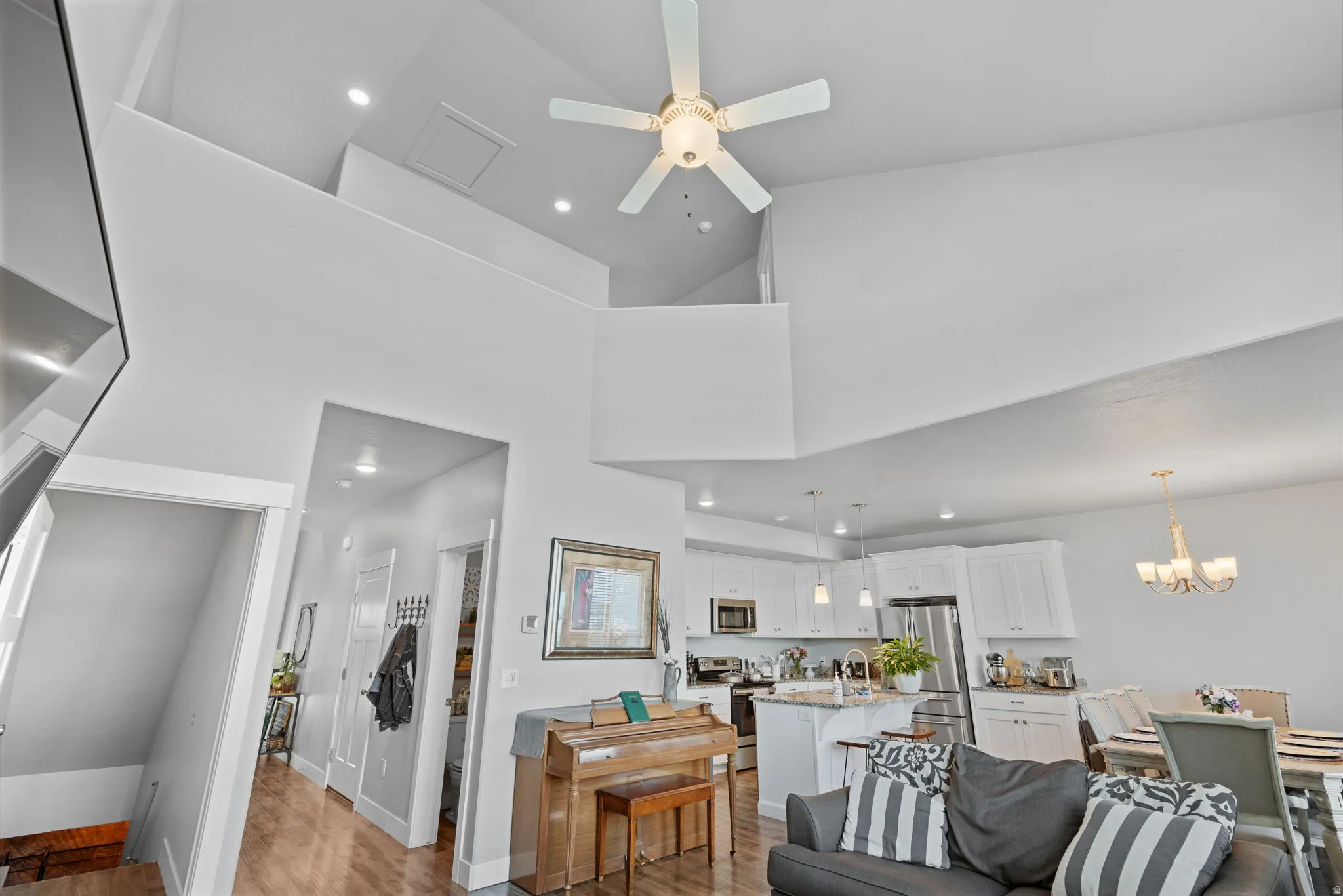 Open-concept living space with vaulted ceilings featuring a ceiling fan and recessed lighting
