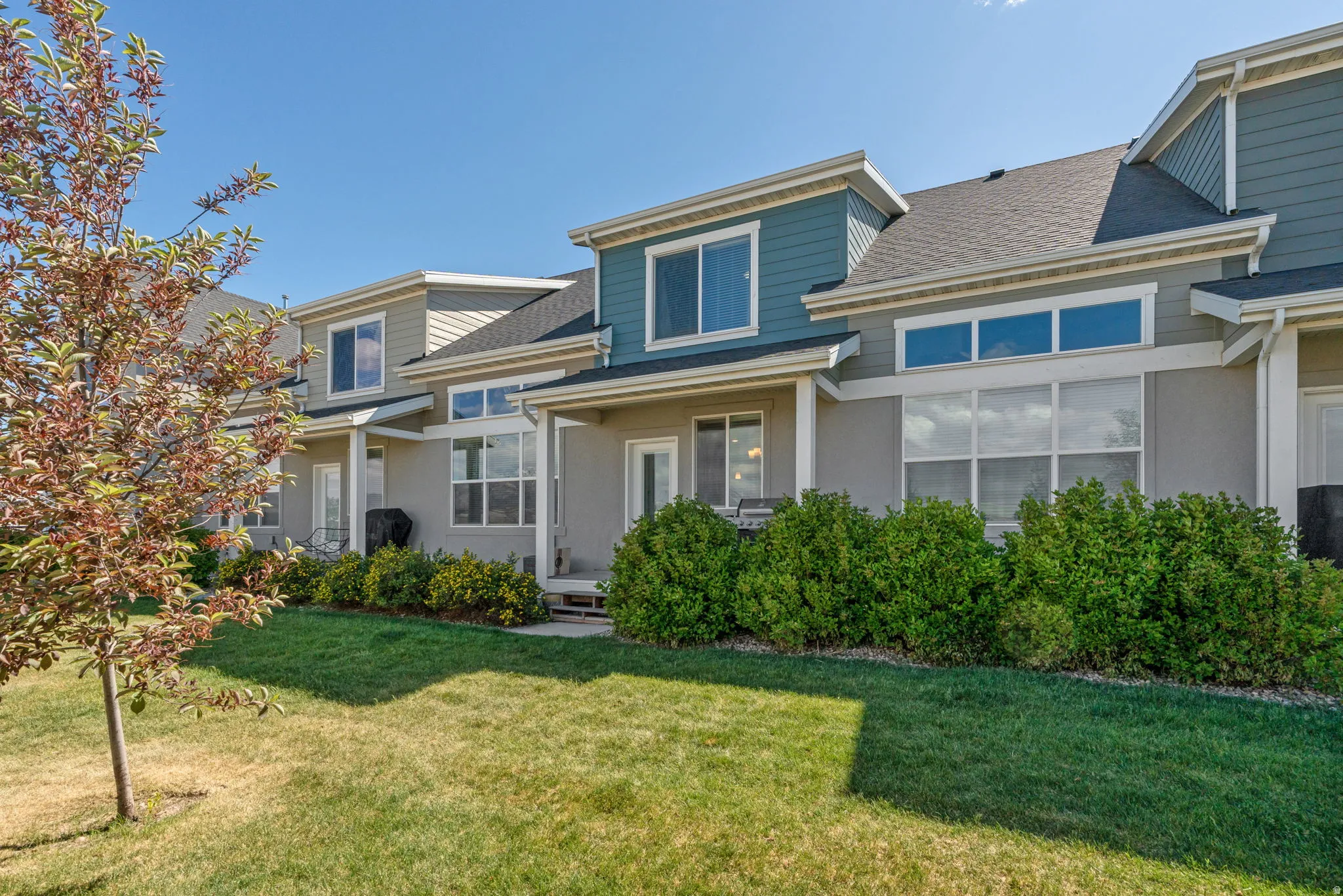 Rear exterior featuring multiple windows, a sliding glass door, and a covered patio area