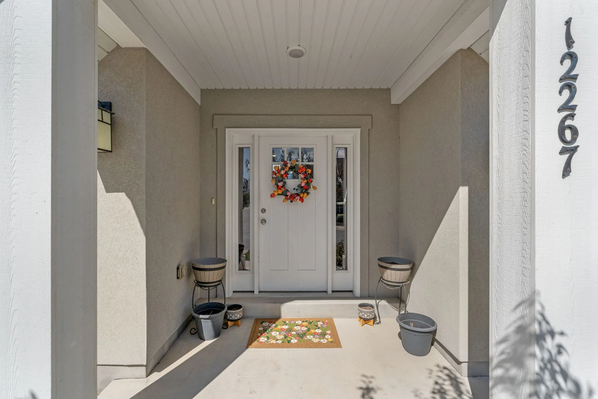 Inviting covered entryway featuring a paneled front door with sidelights, overhead lighting, and concrete flooring