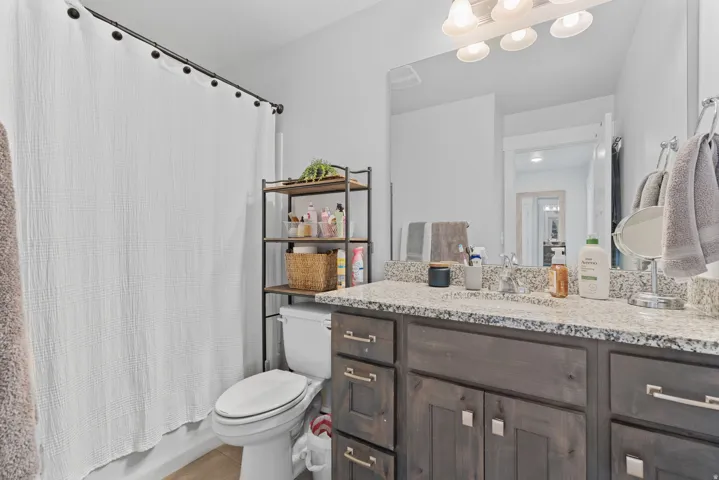 Bathroom vanity featuring a granite countertop with a dual sink and brushed nickel faucets