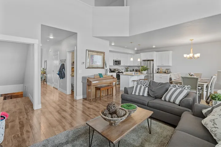 Open concept living space featuring wood-finish flooring, recessed lighting, and a kitchen with white cabinetry and stainless steel appliances