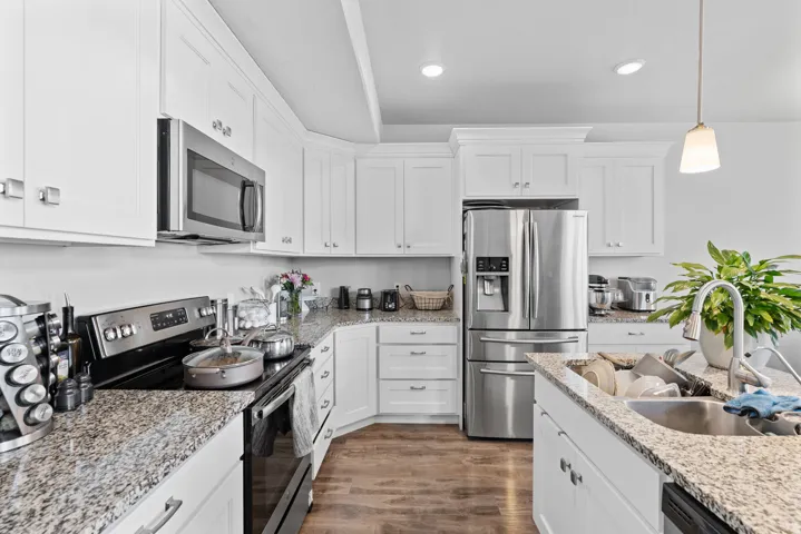 Kitchen featuring white cabinetry, speckled countertops, stainless steel appliances, wood-finish flooring, and recessed lighting