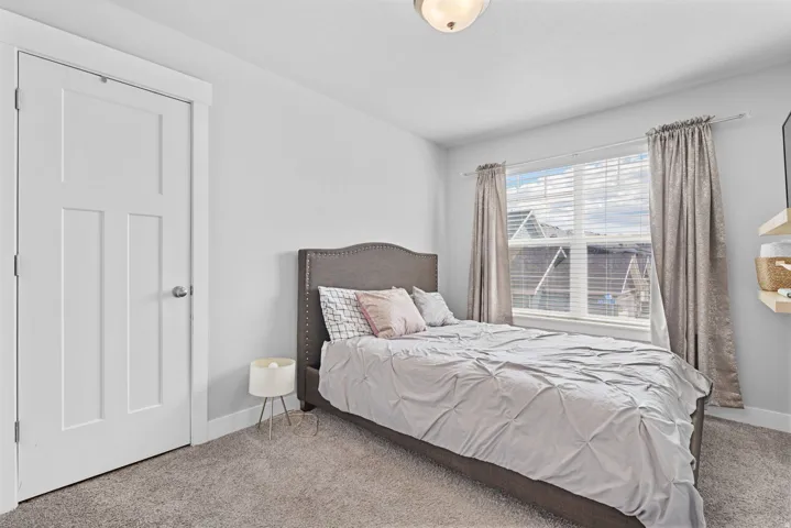 Bright room featuring a single window with blinds, carpeted flooring, and a flush-mount ceiling light