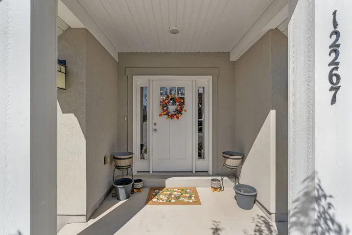 Inviting covered entryway featuring a paneled front door with sidelights, overhead lighting, and concrete flooring
