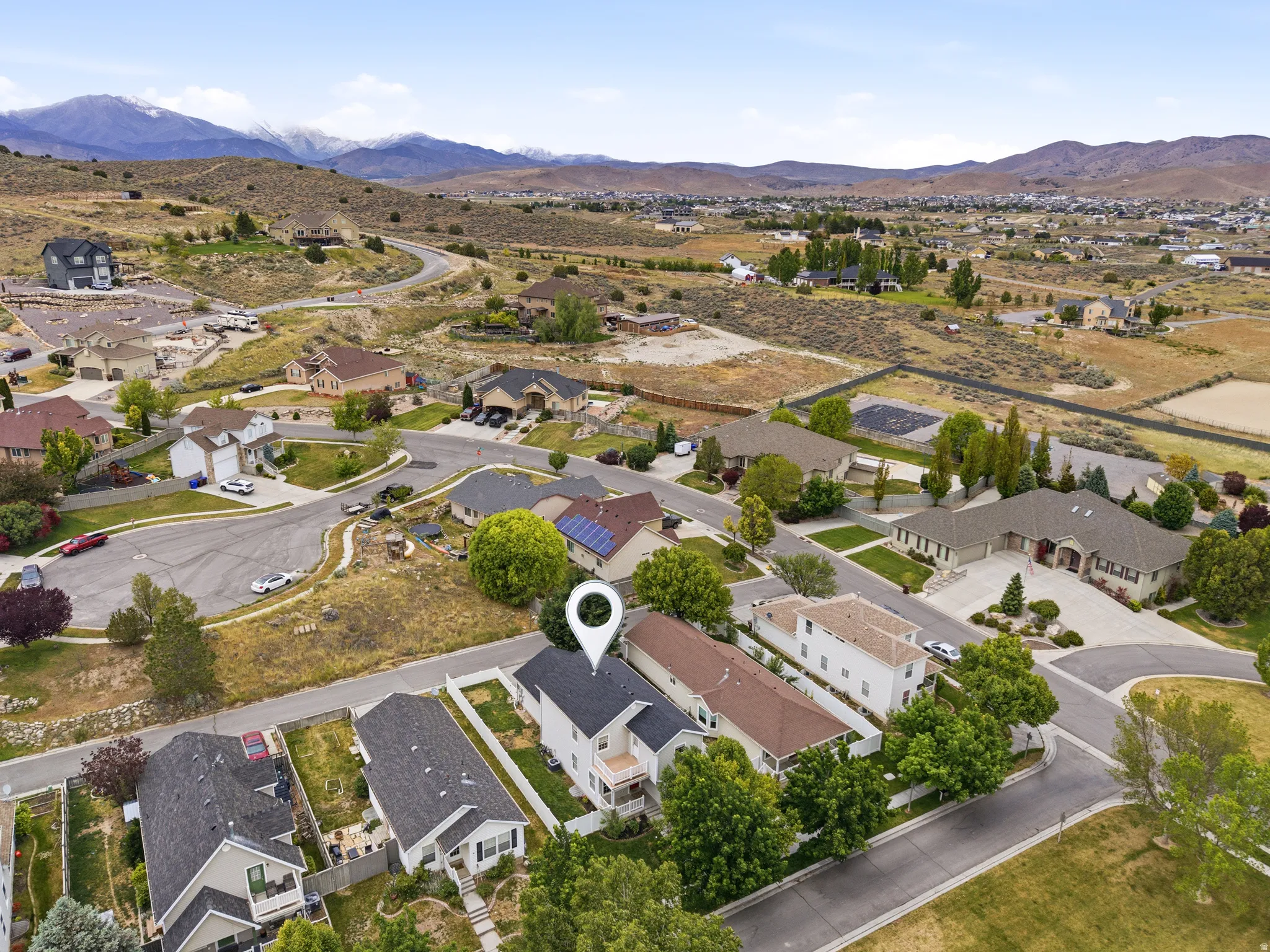 Aerial perspective of the property, showcasing a two-story residence with a light-colored exterior and dark-shingled roof