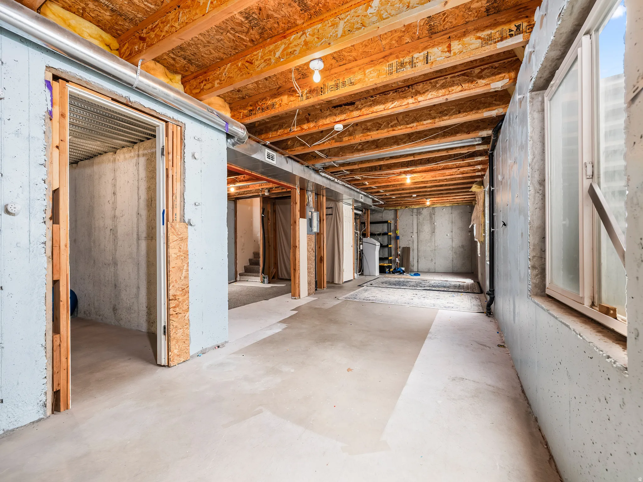 Unfinished basement featuring exposed wood joists, concrete flooring, and concrete block walls