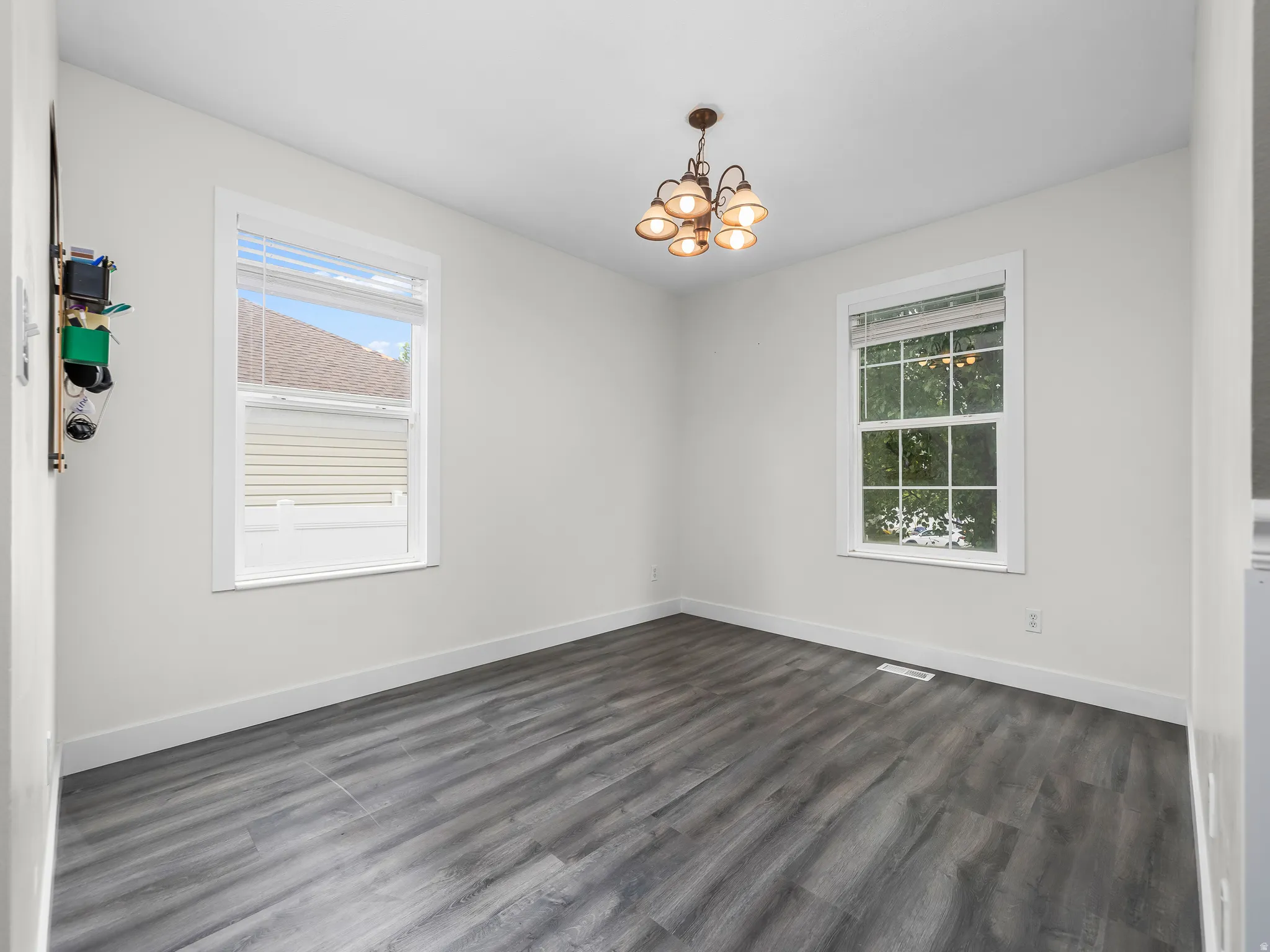 Spacious room featuring wood-finish flooring and a central chandelier