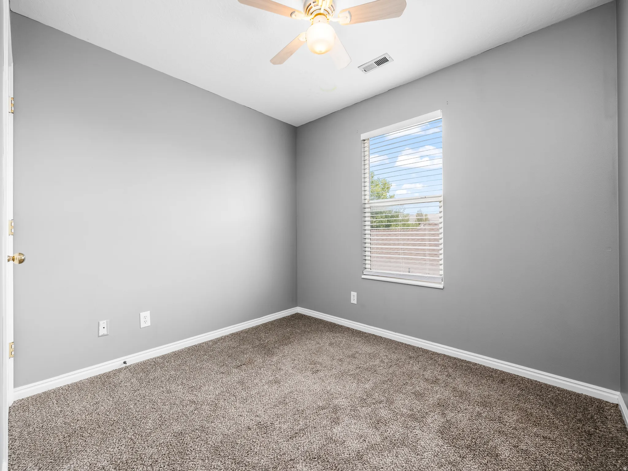 Bed 2 Carpeted interior room featuring a window with horizontal blinds, a ceiling fan with integrated lighting, and neutral wall paint