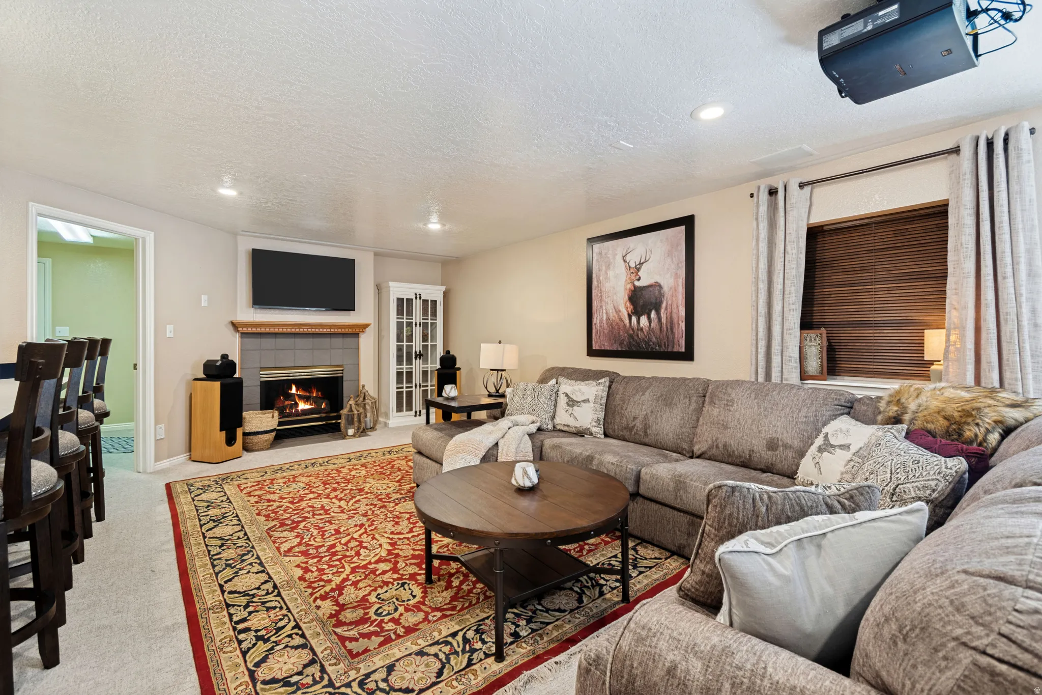 Living area featuring a fireplace with a wood mantle and tile surround, recessed lighting, and a built-in display cabinet