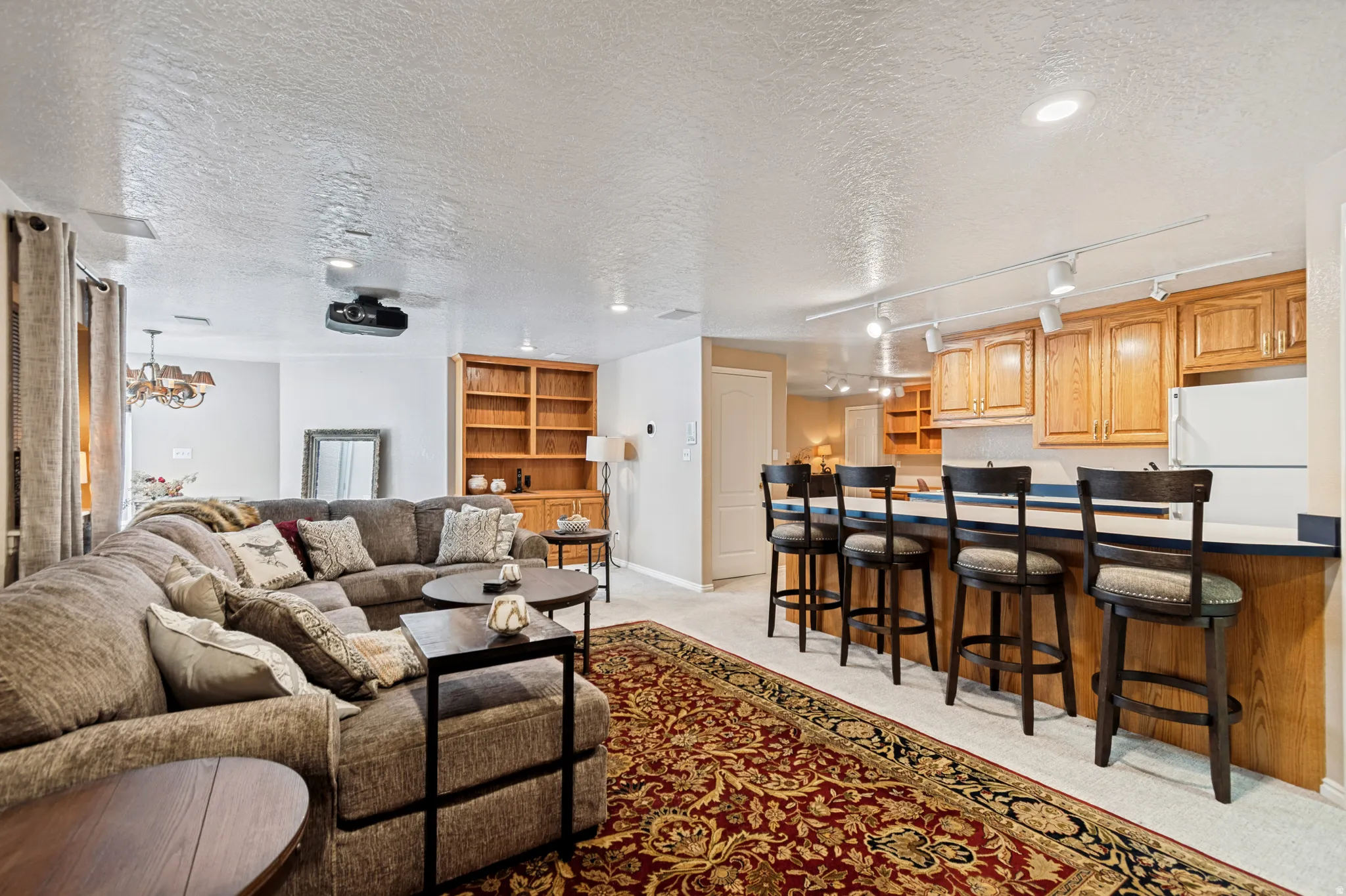 Recreation room featuring track lighting, built-in cabinetry, a wet bar, and a mounted projector