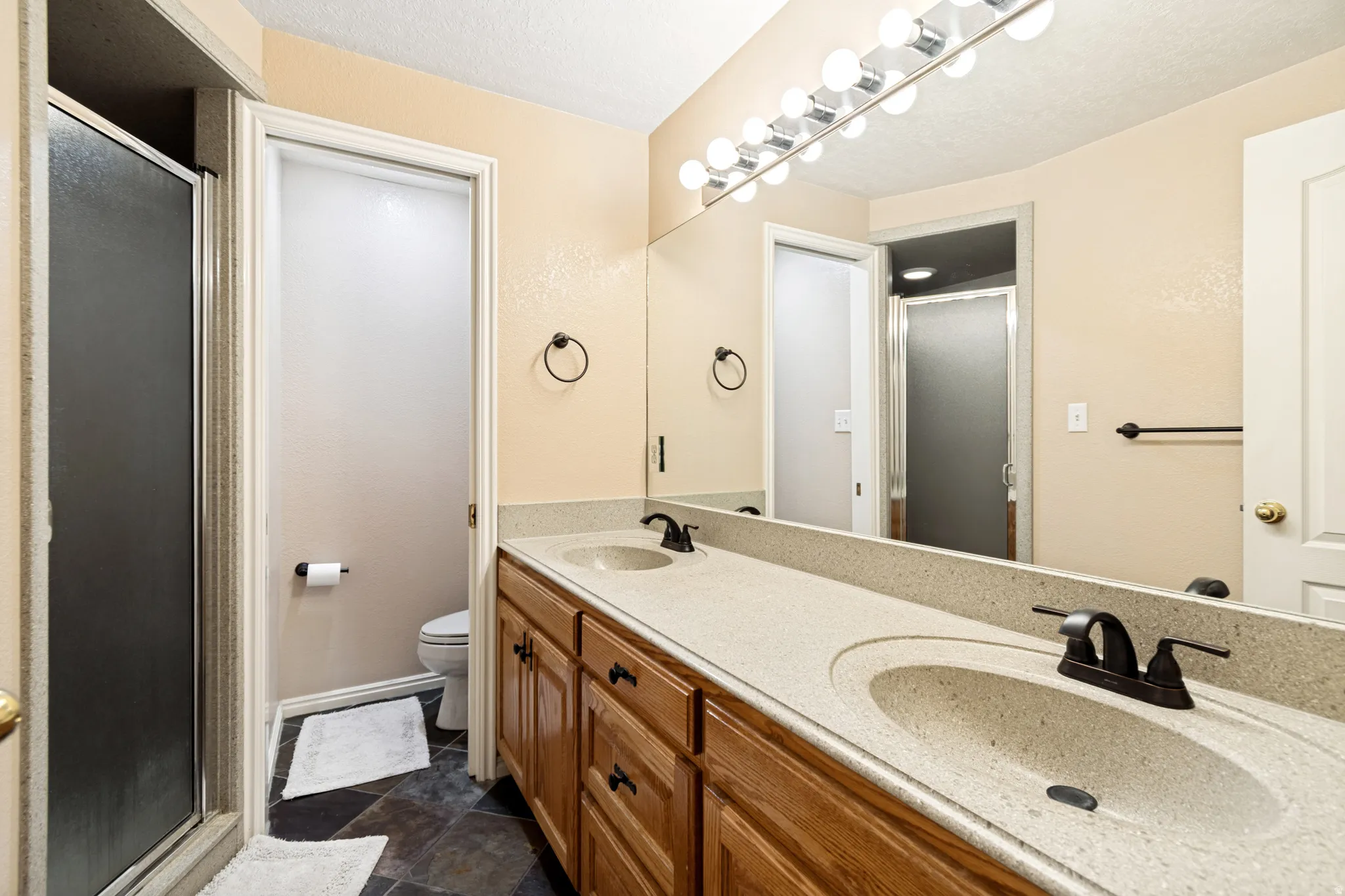 Dual sink vanity with light-colored countertop and wood-finish cabinetry