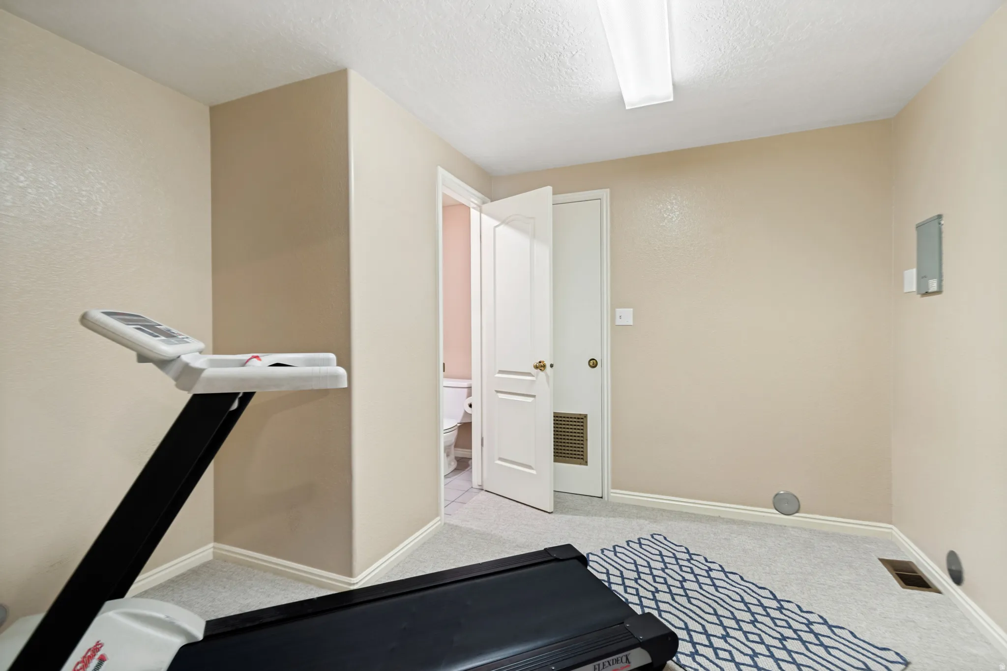 Carpeted room with neutral wall tones and white baseboards