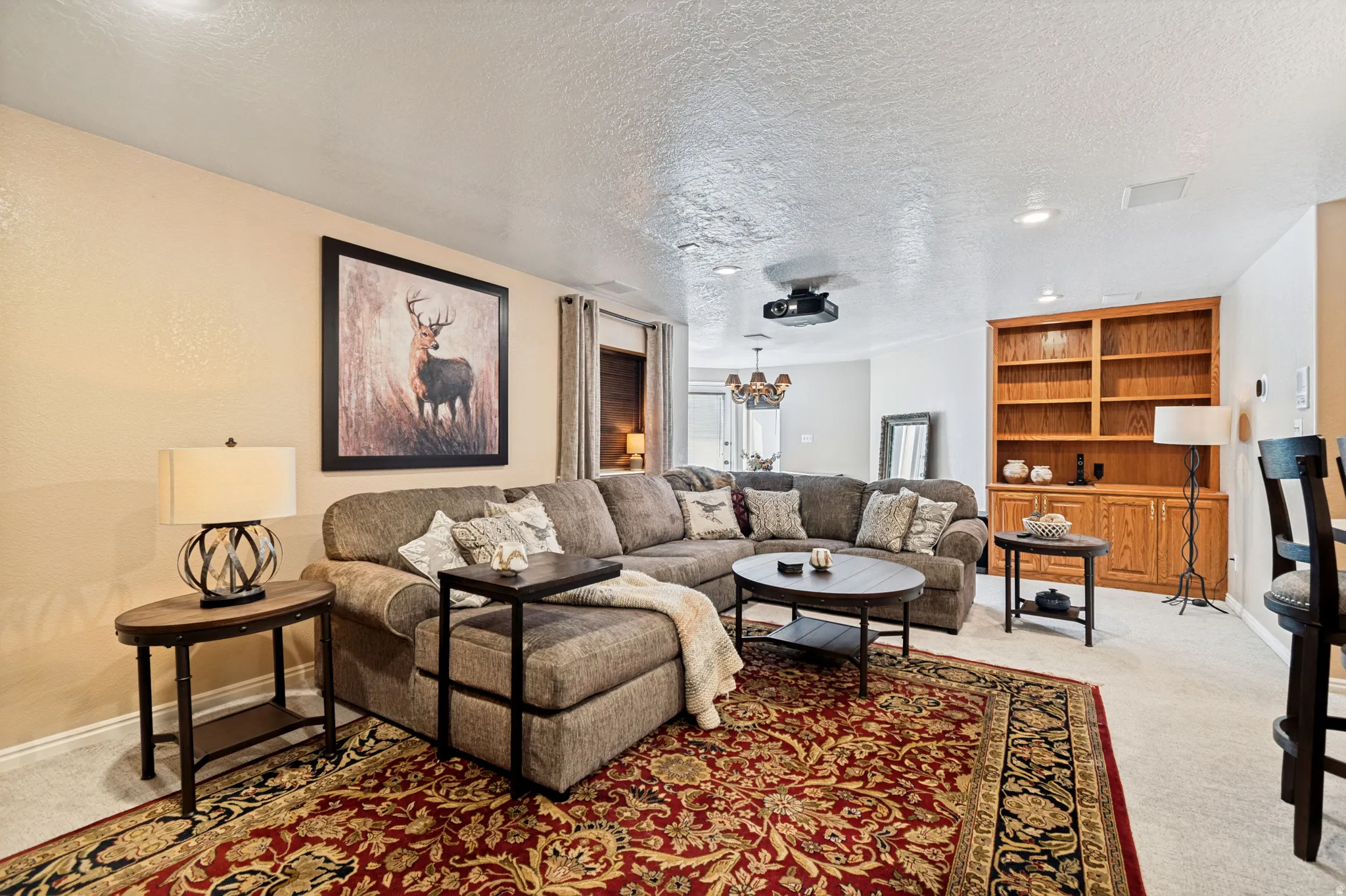 Expansive entertainment space featuring a built-in projector, recessed lighting, and a large built-in wooden bookshelf with cabinet storage