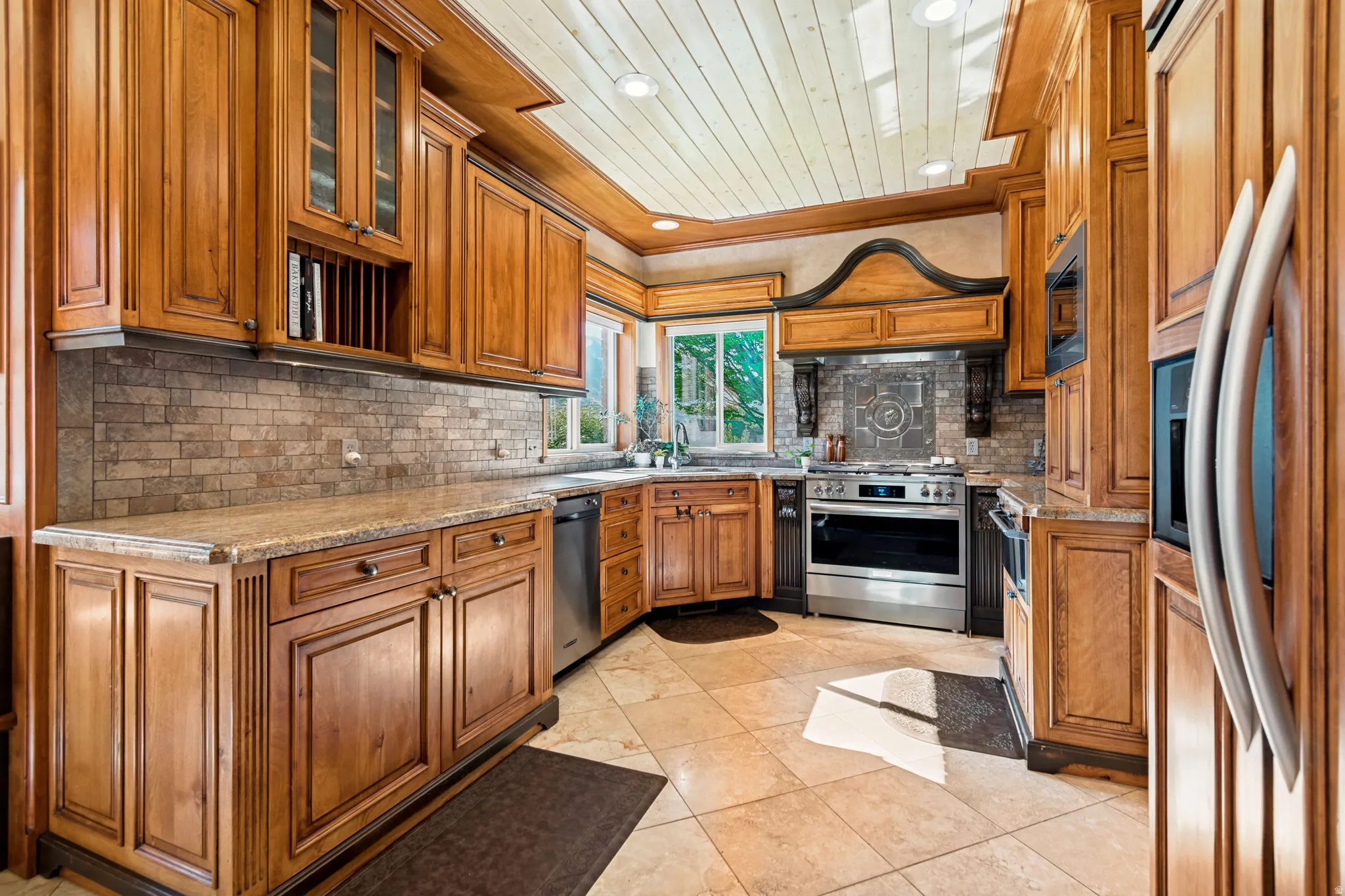 Kitchen featuring extensive wood cabinetry, granite countertops, subway tile backsplash, stainless steel appliances, and tile flooring