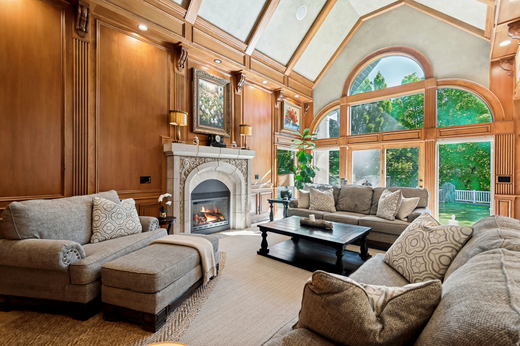 Spacious living area featuring intricate wood paneling, a soaring vaulted ceiling with exposed beams, and a grand stone fireplace