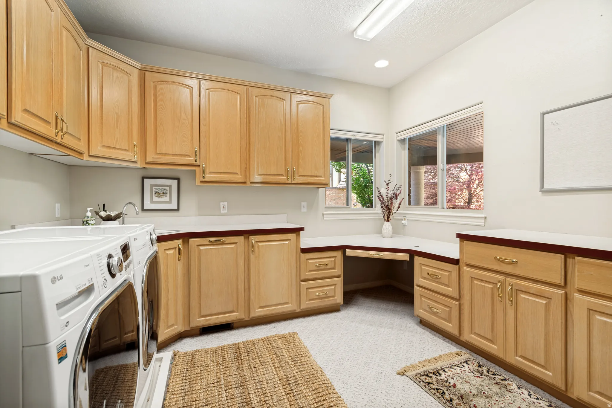 Utility room featuring extensive wood cabinetry, light-toned countertops, and a built-in desk area