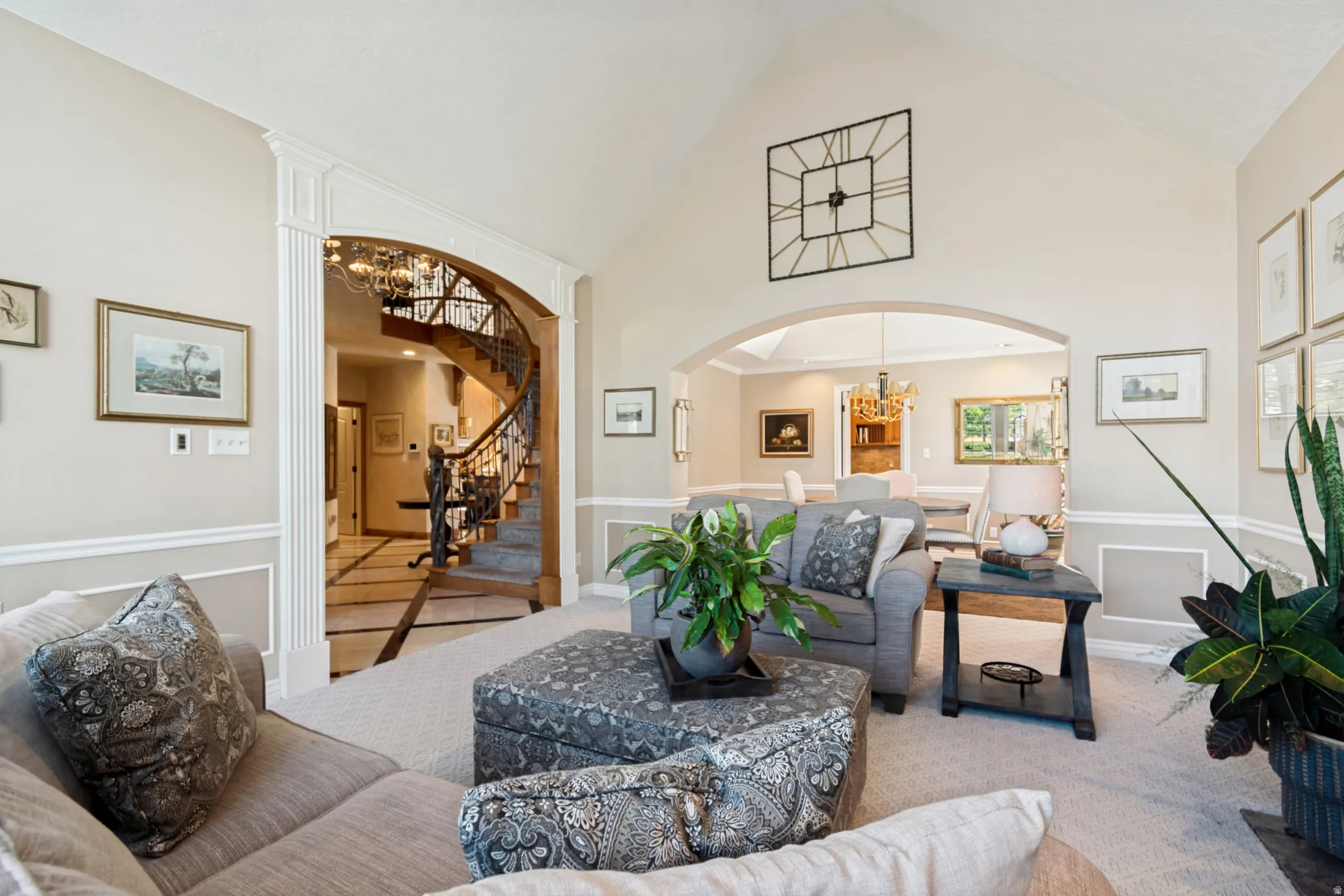 Vaulted living area featuring a decorative archway, recessed lighting, and a sweeping wooden staircase with wrought iron balusters