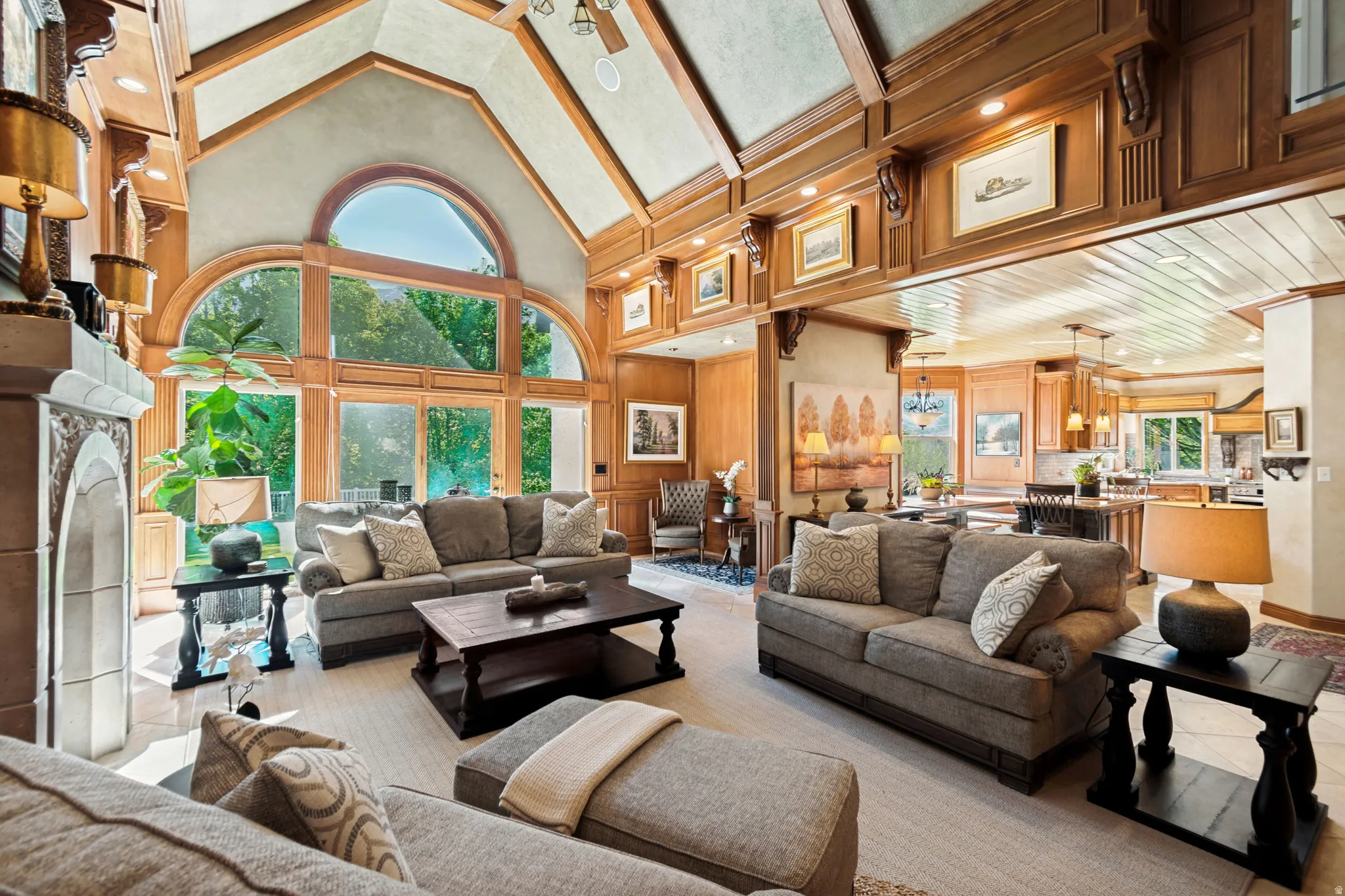 Great room featuring vaulted wood-paneled ceilings, a floor-to-ceiling arched window array, an ornate fireplace with a mantel, and wood-finish flooring