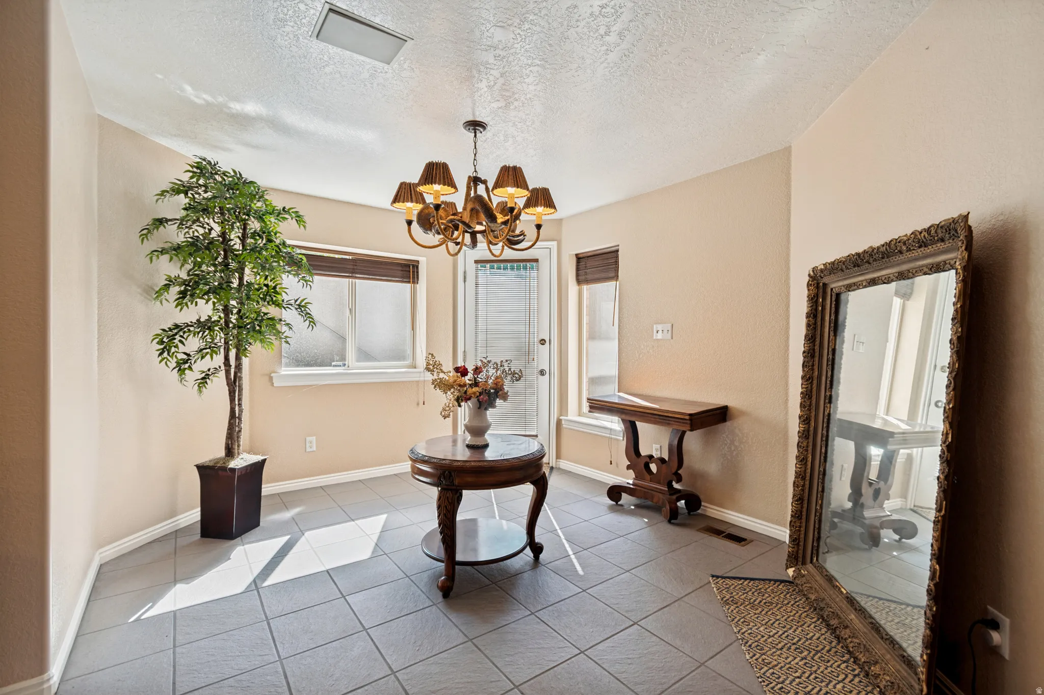 Dining area featuring neutral wall tones, large format gray tile flooring, and a decorative chandelier
