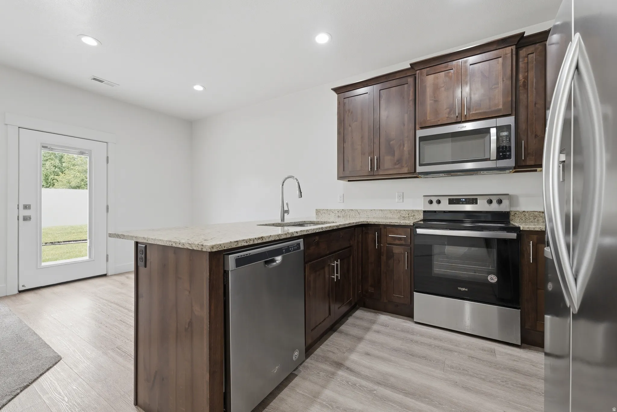 Modern kitchen featuring wood-finish cabinetry, stainless steel appliances, and granite countertops