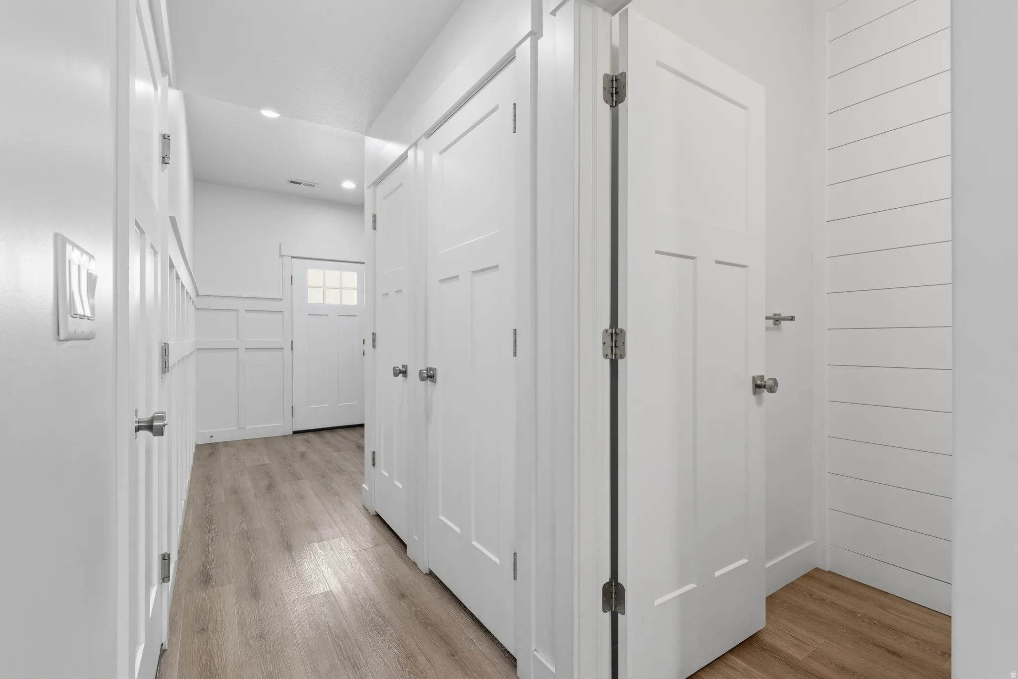 Hallway featuring wood-finish flooring, recessed lighting, and white paneled doors