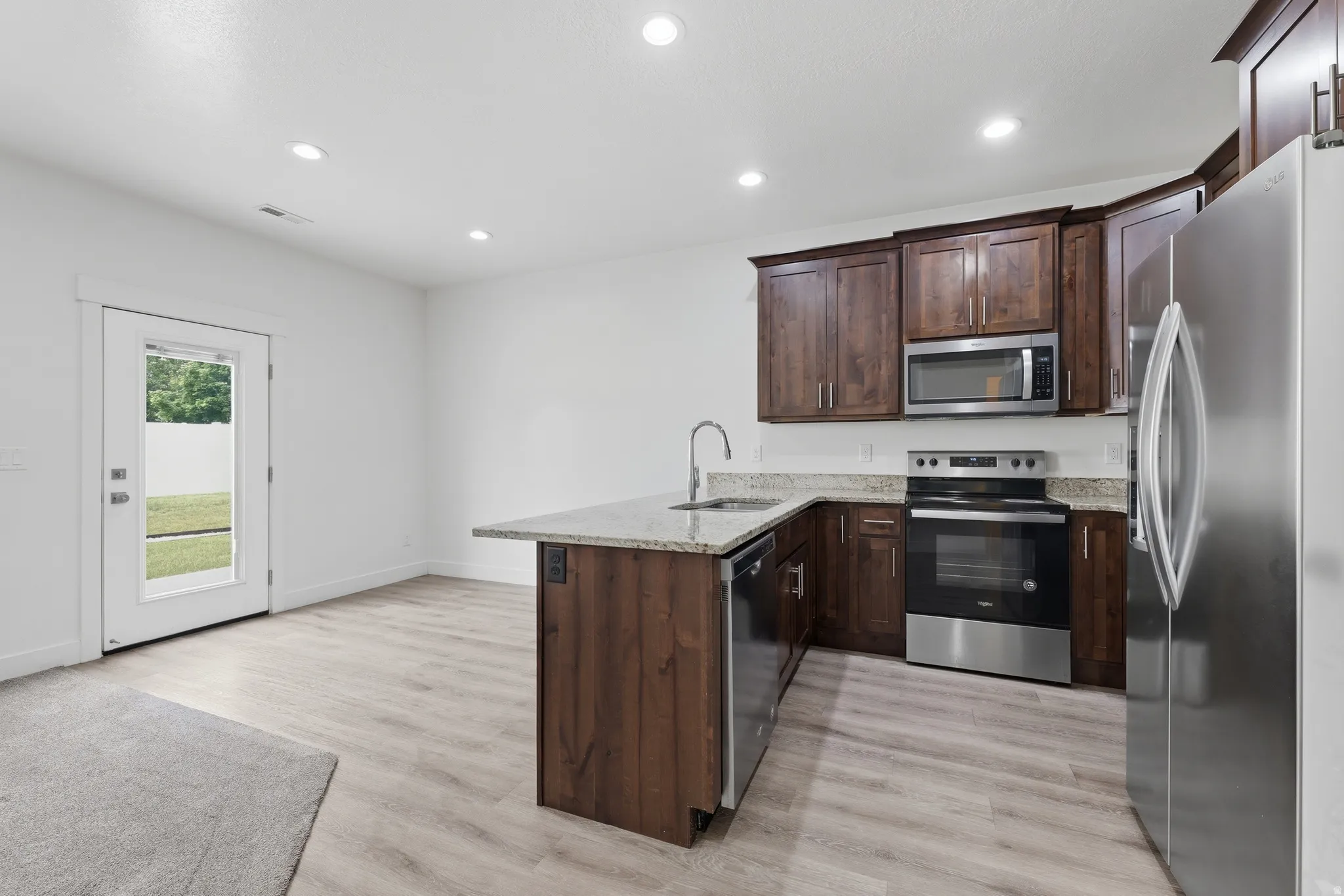 Kitchen area featuring dark wood-finish cabinetry, stainless steel appliances, and light-toned countertop surfaces