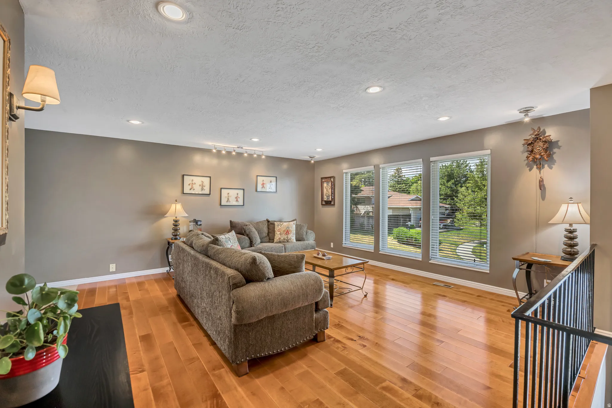 Open living area featuring wood-finish flooring, recessed lighting, and a wall of three windows