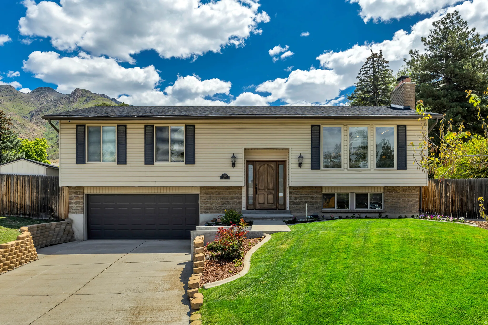 Split-level residence featuring a two-car garage, stone facade, and a prominent front door with sidelights