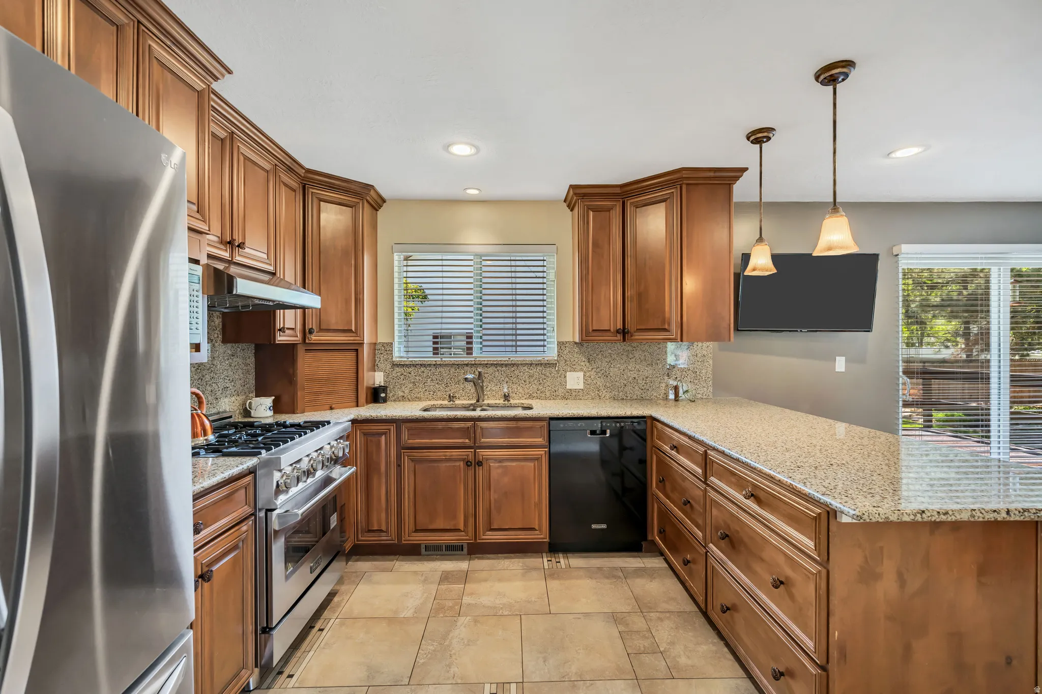 Kitchen featuring warm wood cabinetry, light-toned granite countertops, and stainless steel appliances