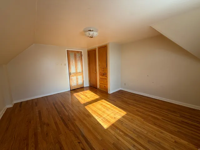 Hardwood flooring throughout featuring a built-in wood cabinet with drawers, a separate wood door, and a flush mount ceiling light fixture