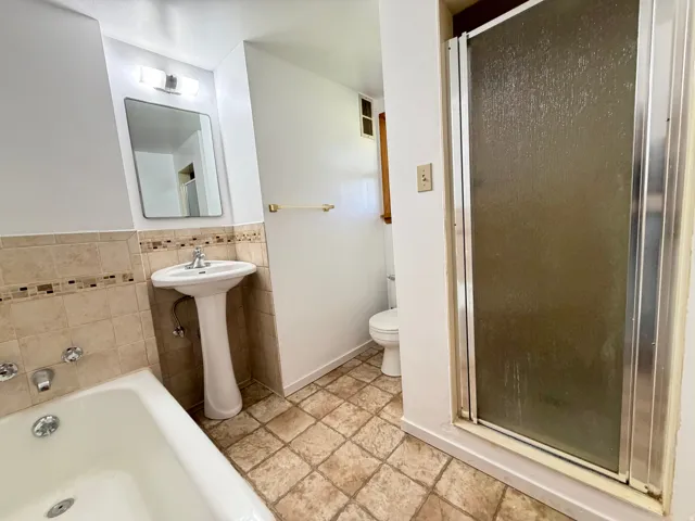 Bathroom featuring a pedestal sink, a bathtub with wall-mounted fixtures, and a glass-enclosed shower