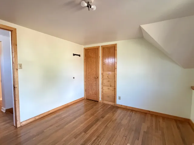 Interior space featuring wood-finish flooring, light-toned walls, and a built-in wooden cabinet with drawers