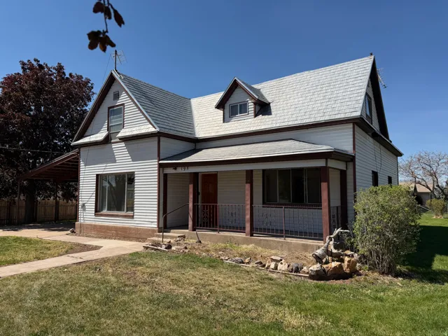 Two-story residence featuring white siding, a covered front porch, and a dormer window