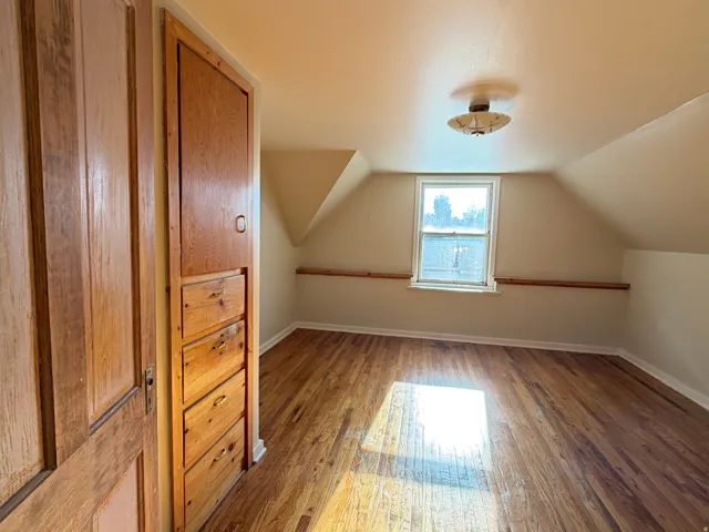 Room featuring wood-finish flooring, a double-hung window, and a built-in wood cabinet with drawers