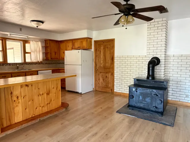 Kitchen and living area featuring a wood-burning stove with brick surround
