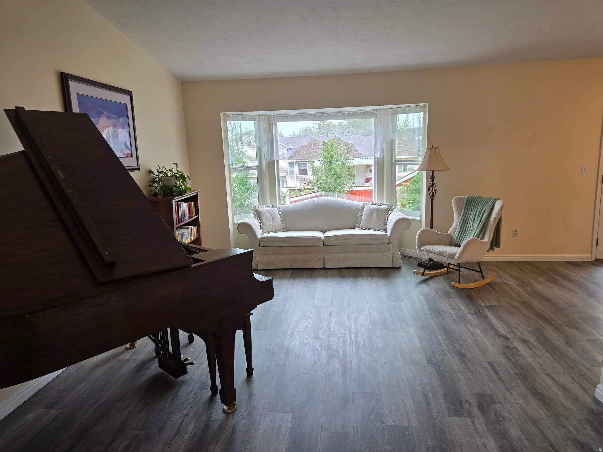 Spacious living area featuring LVP flooring, a large bay window, and neutral wall tones