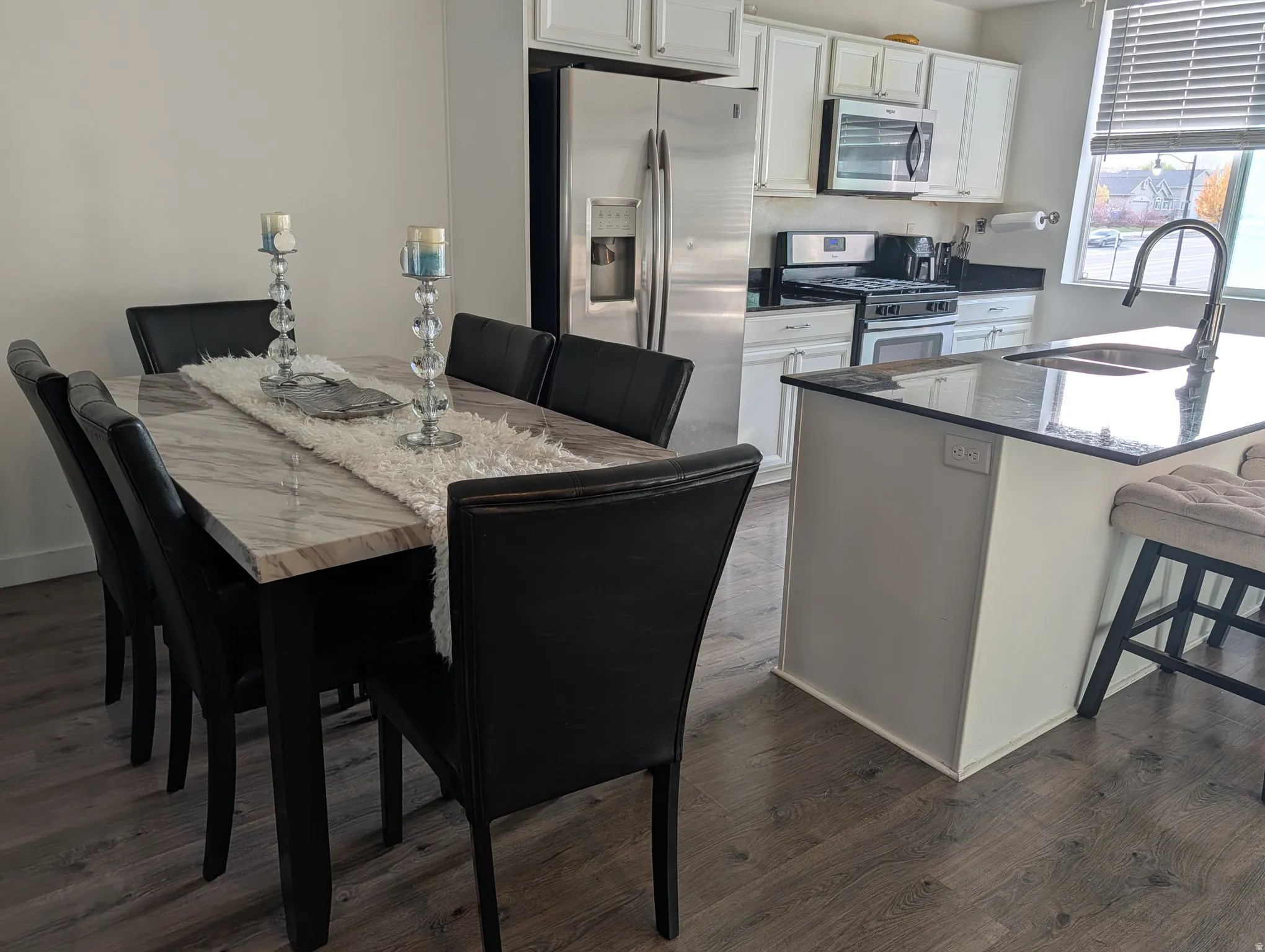 Modern kitchen featuring white cabinetry, stainless steel appliances, and dark granite countertops