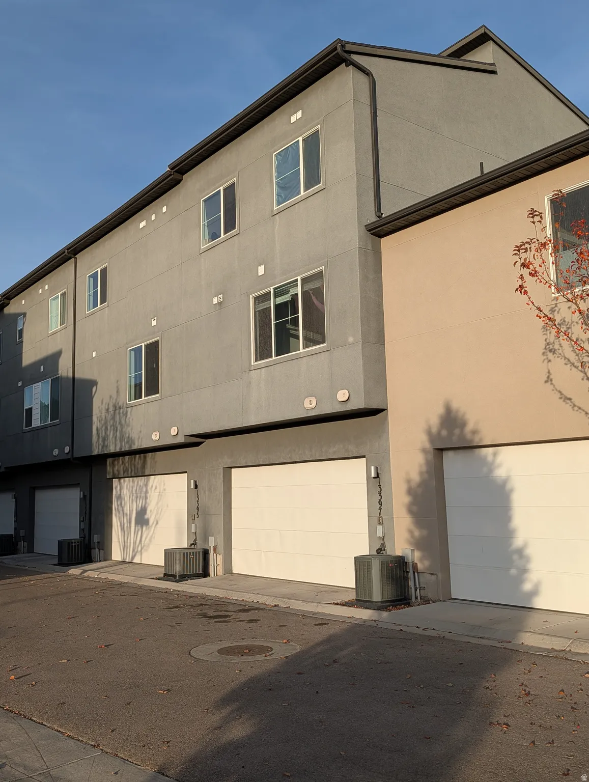Multi-story building featuring a stucco exterior, multiple window placements, and individual garage access at ground level
