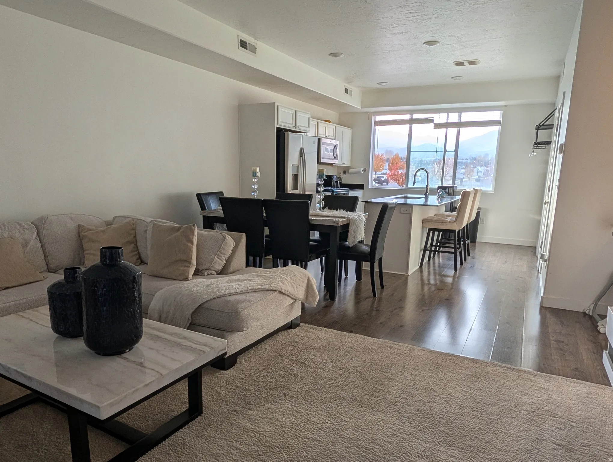 Open-concept living area featuring wood-finish flooring, recessed lighting, and a large window