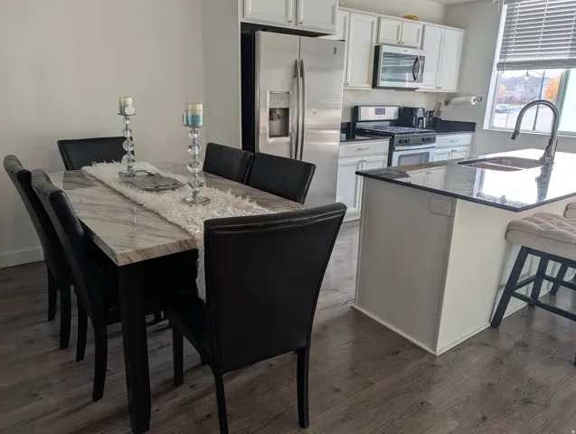 Modern kitchen featuring white cabinetry, stainless steel appliances, and dark granite countertops