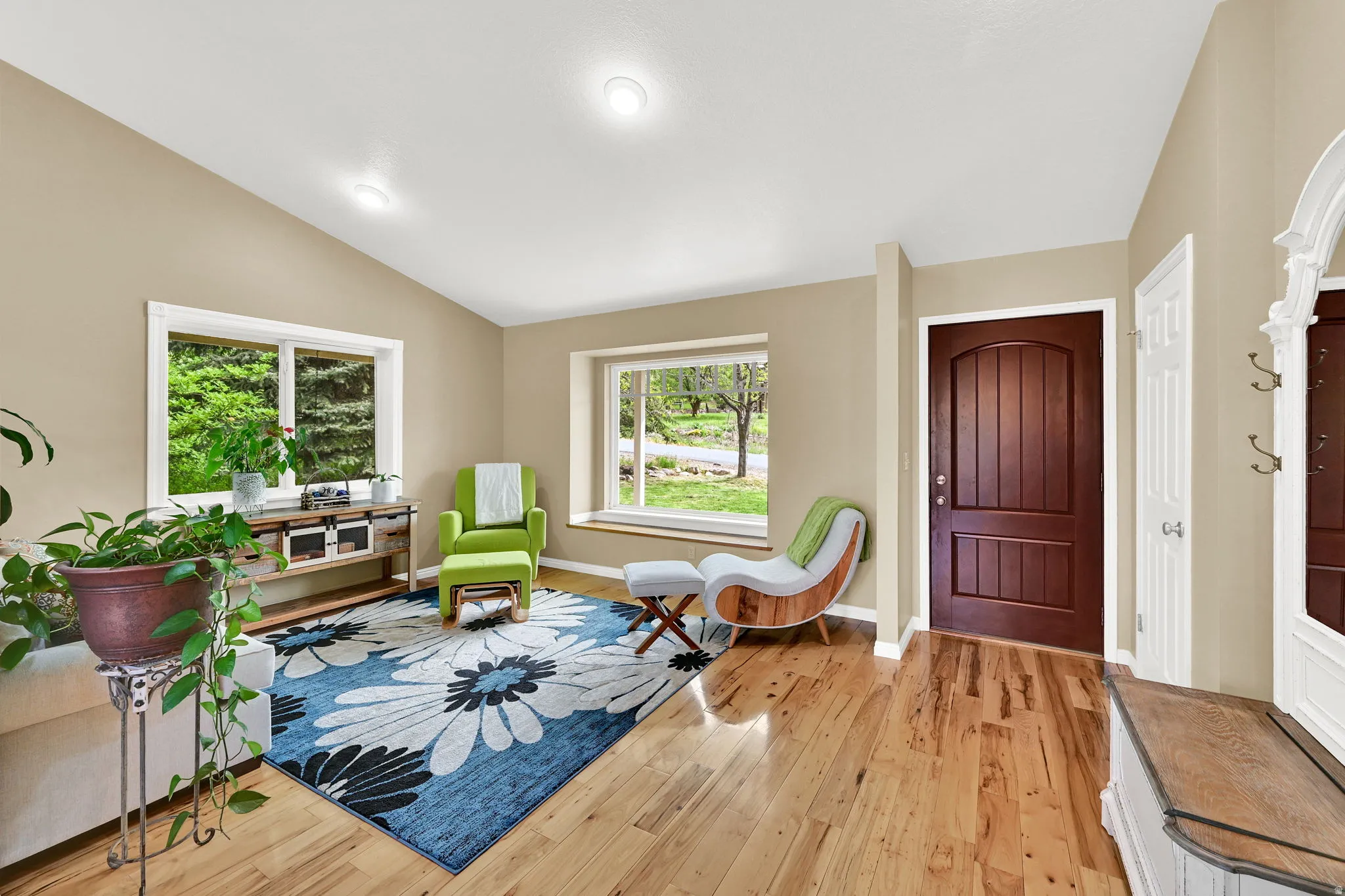 Entryway and living area featuring hardwood flooring, vaulted ceiling, recessed lighting, and large windows with white trim