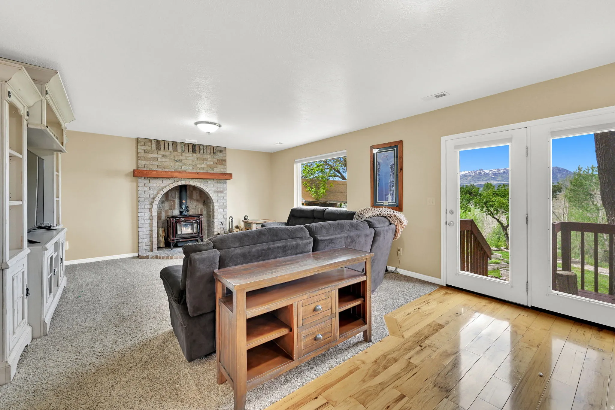 Living area featuring a brick fireplace with a wood-burning stove, a wood mantel, and a built-in media cabinet